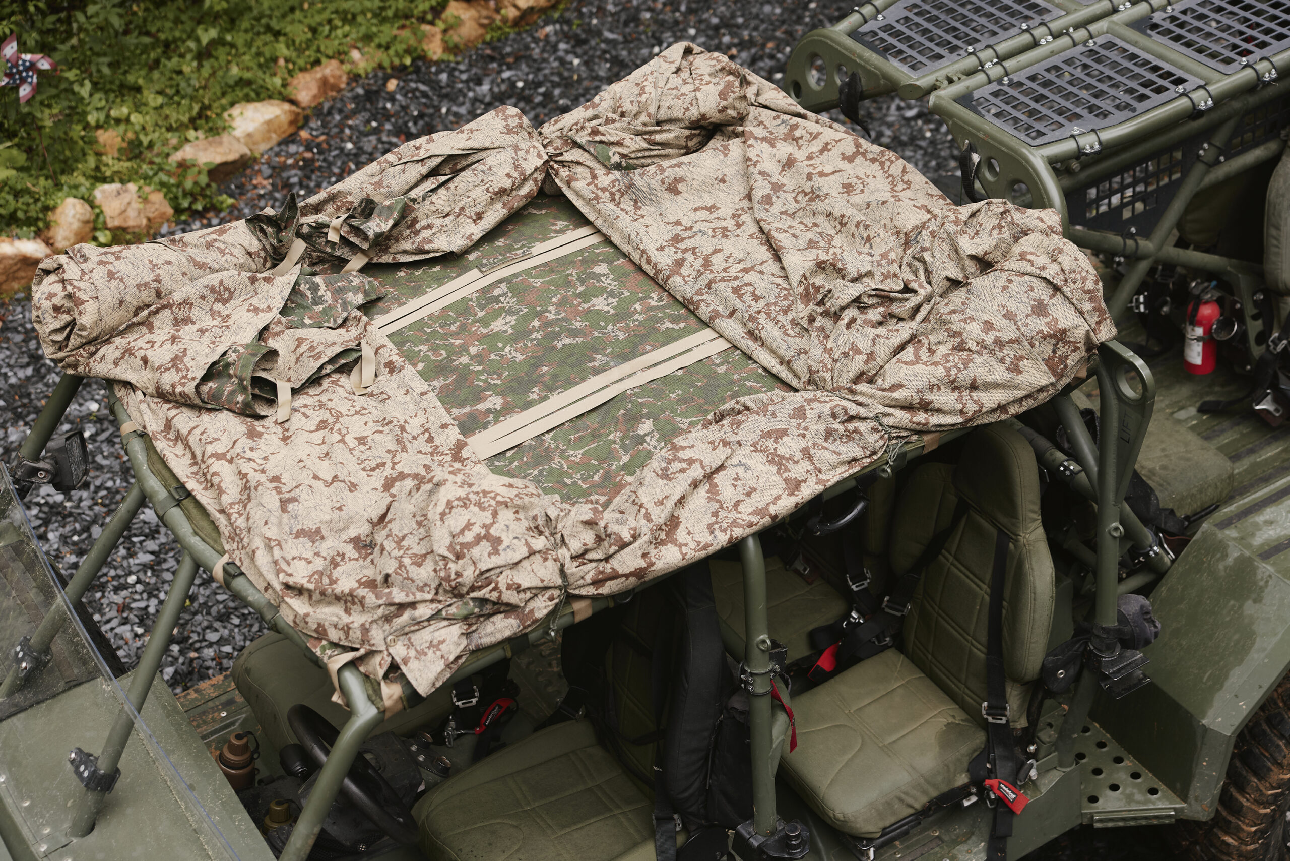 Field operator in camouflage among trees