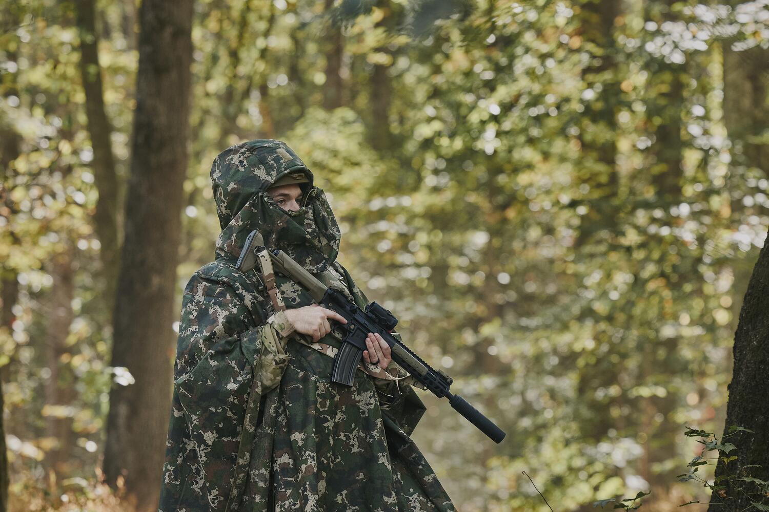 Camouflaged field operator moving through a forest