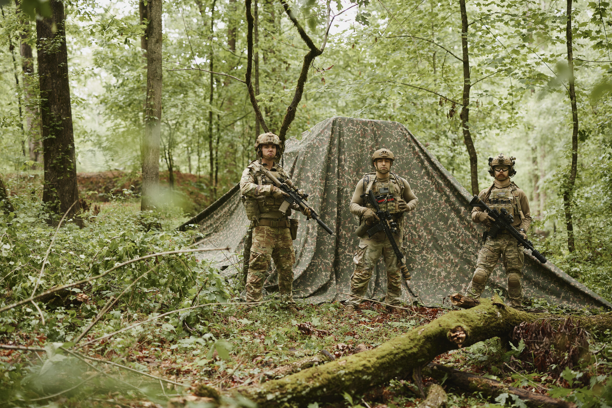 Field operator in camouflage among trees