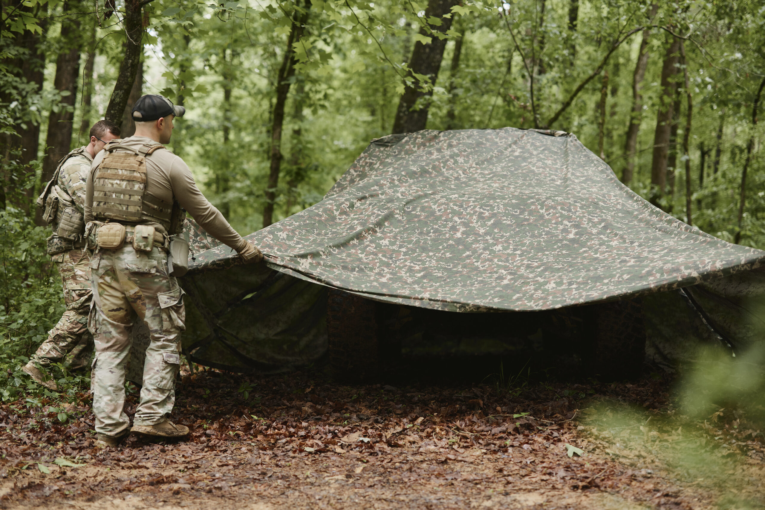 Field operator in camouflage among trees