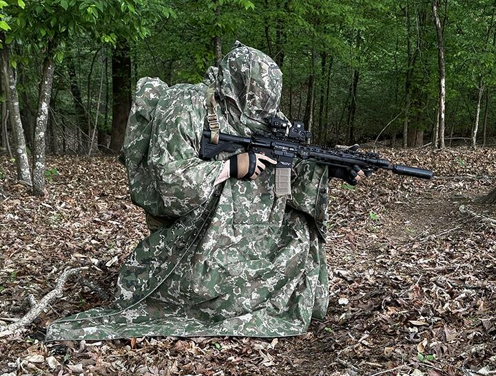 Camouflaged field operator moving through a forest