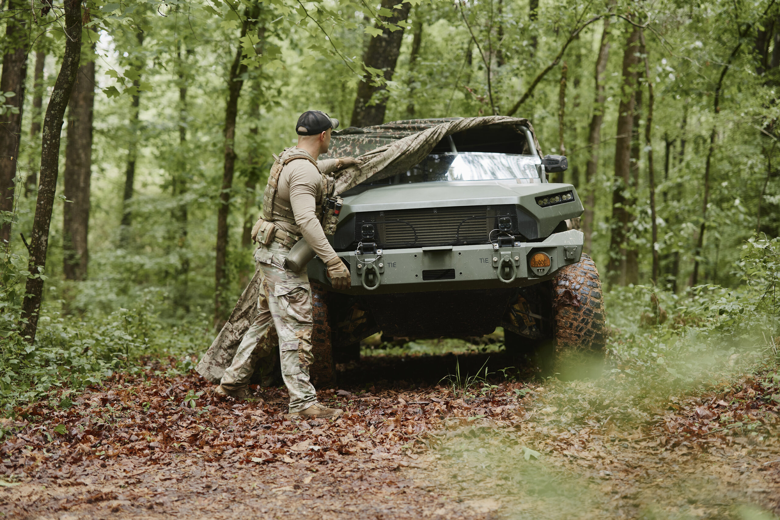 Field operator in camouflage among trees