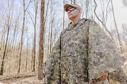 Camouflaged field operator moving through a forest