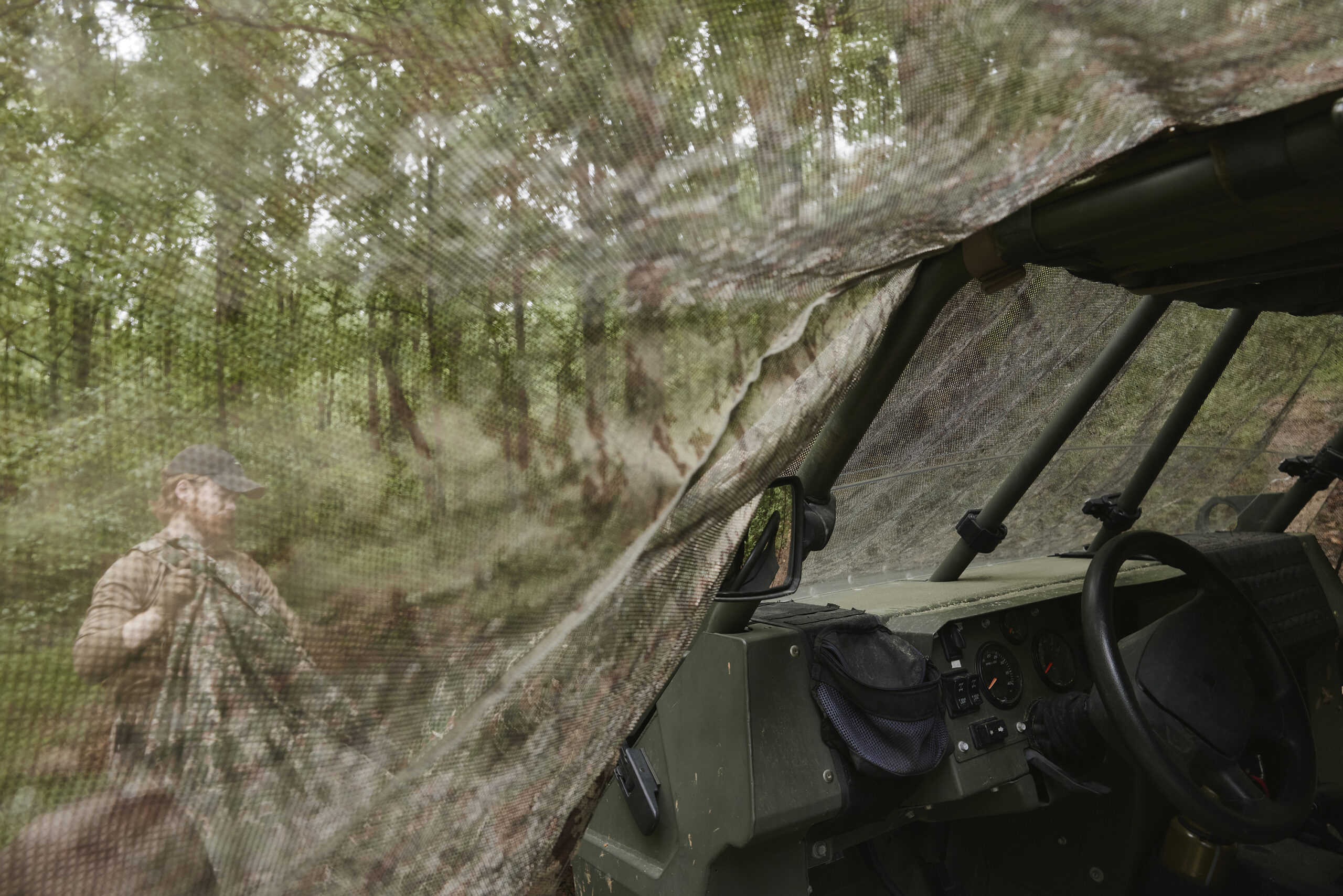 Field operator in camouflage among trees