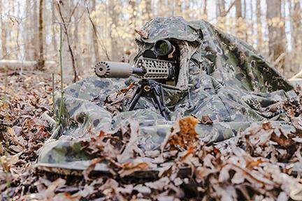 Camouflaged field operator moving through a forest
