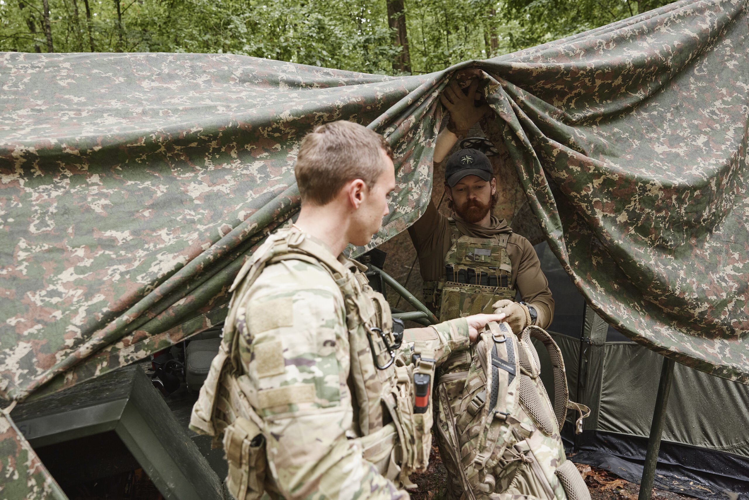 Field operator in camouflage among trees