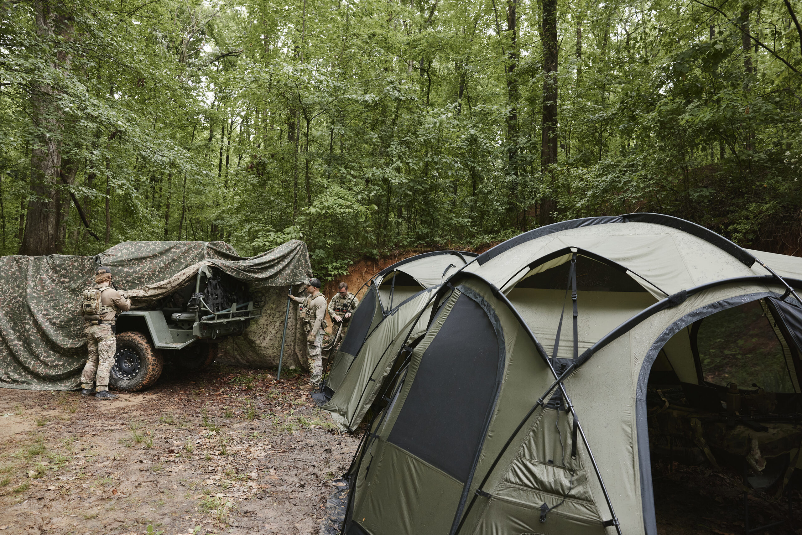 Field operator in camouflage among trees