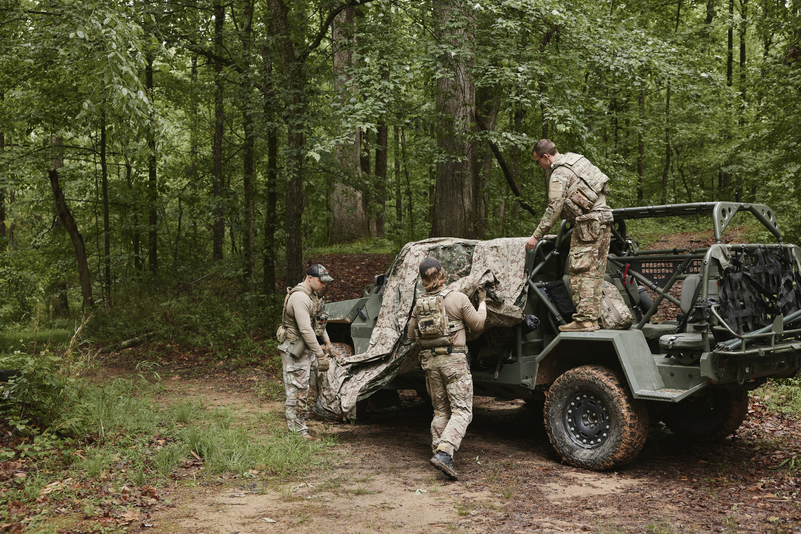 Field operator in camouflage among trees
