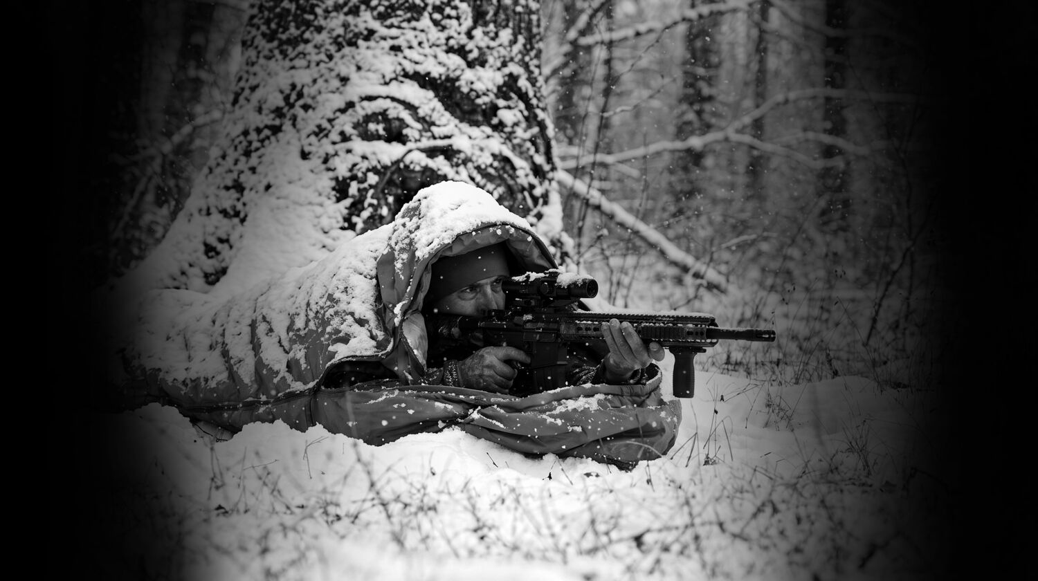 Field operator in camouflage among trees