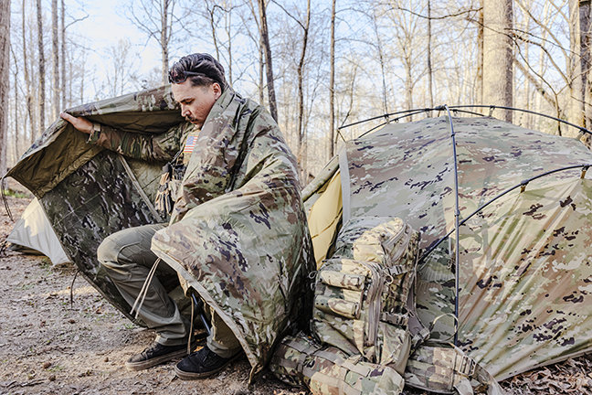 Camouflaged field operator moving through a forest