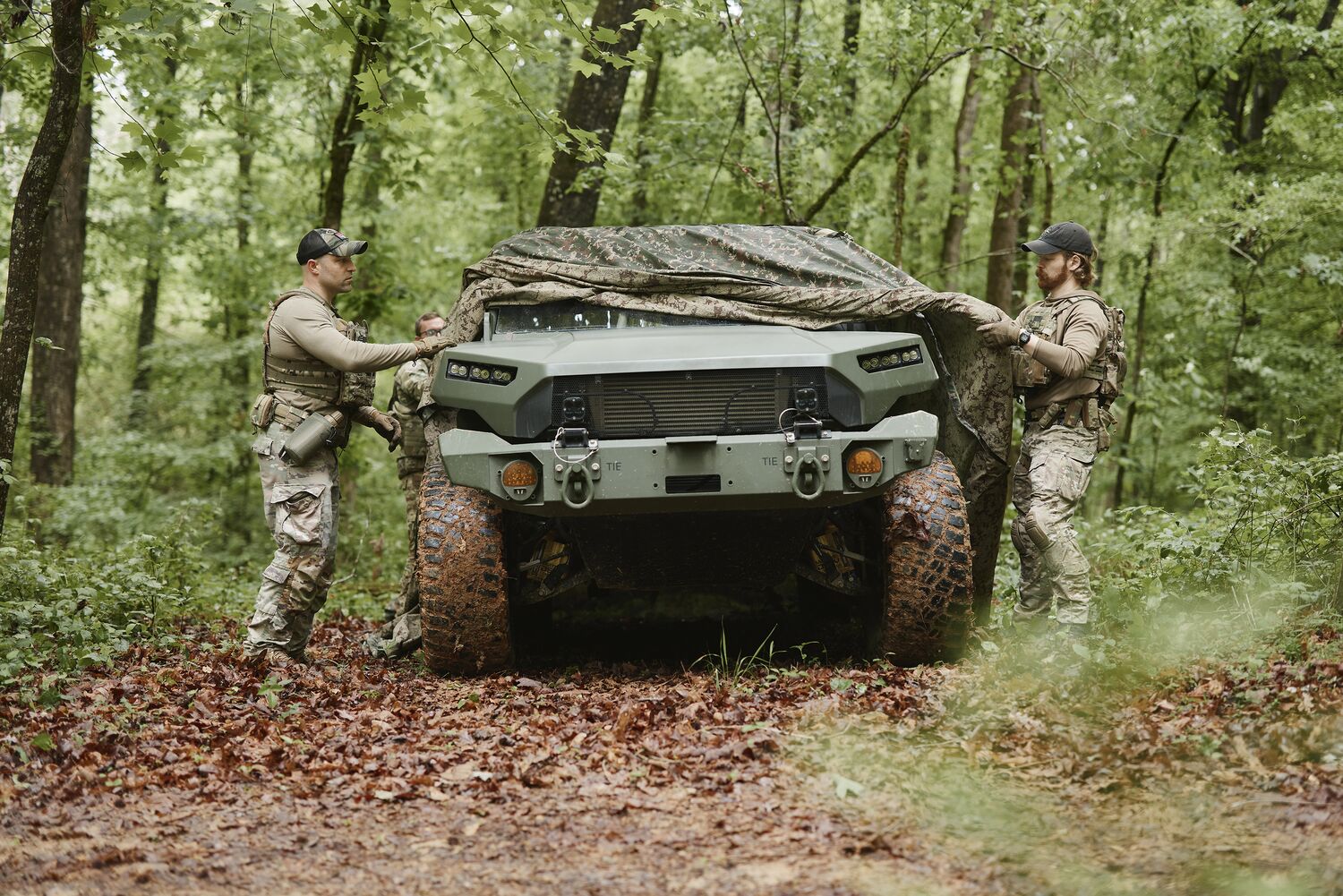 Field operator in camouflage among trees