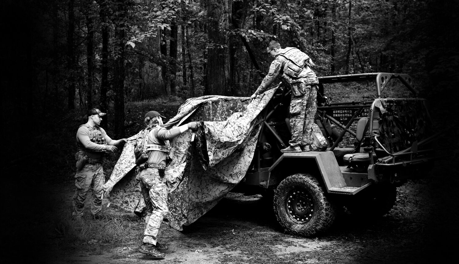 Field operator in camouflage among trees