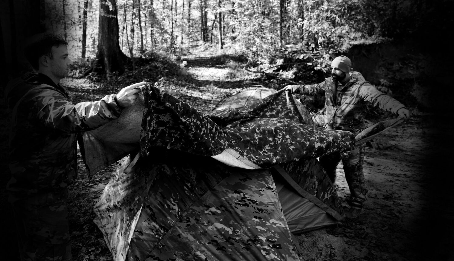 Field operator in camouflage among trees