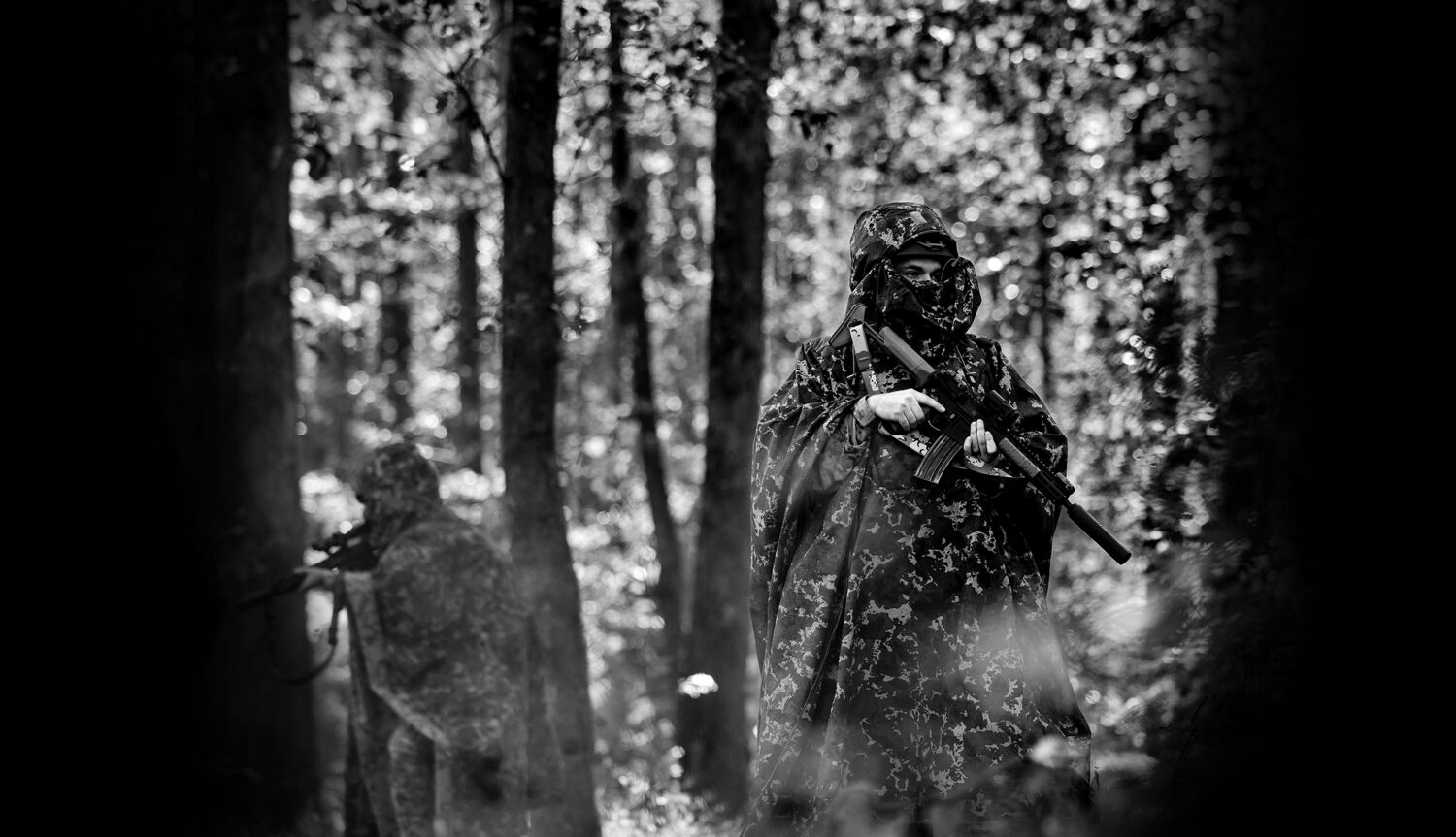 Field operator in camouflage among trees